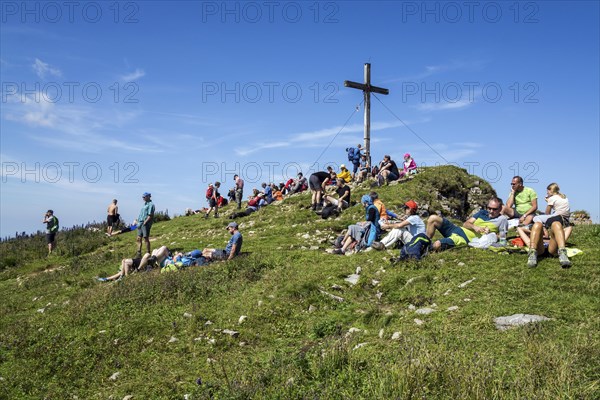 Mountain hikers rest at the summit cross of the Hoher Ifen mountain