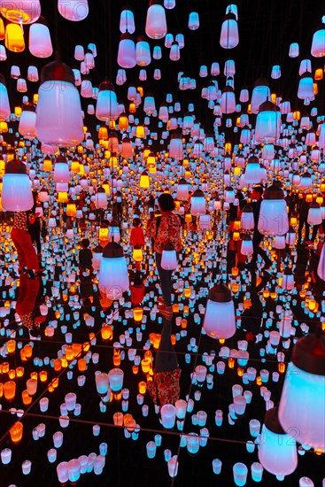 Visitors in the middle of a light installation with brightly lit lamps