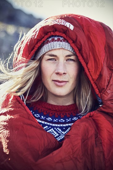 Portrait of a young woman in a red sleeping bag looking into the camera