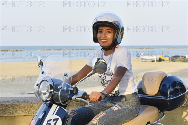 Woman on Vespa 125 Primavera in the port of Penelope