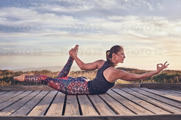 Young woman on the beach doing yoga exercises
