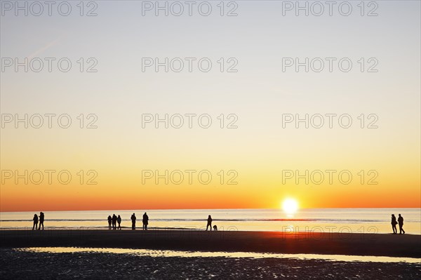 People on the beach at sunset over the North Sea