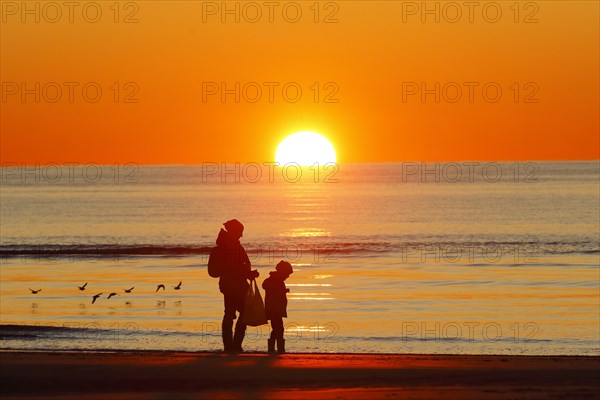 Mother and child on the beach at sunset
