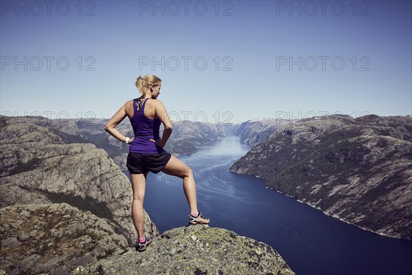 Young woman enjoying the view over the fjord from the top of Preikestolen