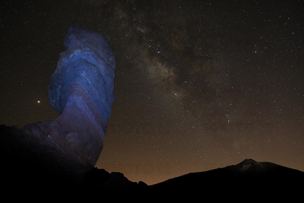 Illuminated Roque Cinchado and Pico del Teide with starry sky