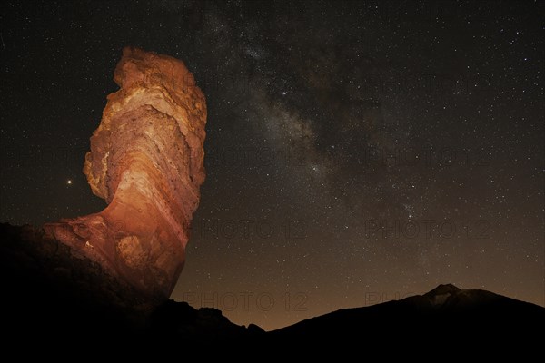 Illuminated Roque Cinchado and Pico del Teide with starry sky