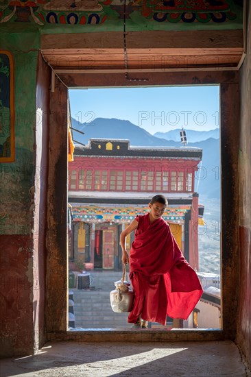 Young monk bringing butter milk tea to the prayer hall