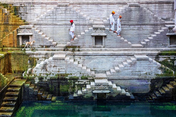 Three men walking down the steps at the stepwell Toorji Ka Jhalra in Jodhpur