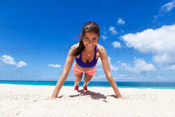 Woman doing push ups on beach