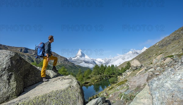 Hiker stands on rocks and looks into the distance