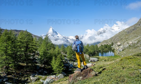 Hiker stands on rocks and looks into the distance