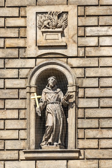 Statue of St. Francis of Assisi in a niche on the facade of the Church of the Knights of the Cross