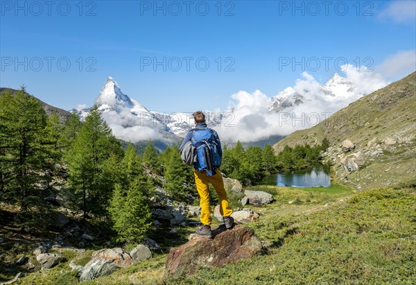 Hiker stands on rocks and looks into the distance
