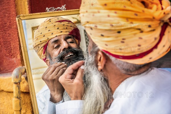 Portrait of a man fixing his beard in a mirror