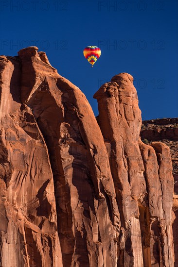 Hot air balloon flying between buttes