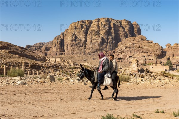 Two moroccan people riding on a donkey