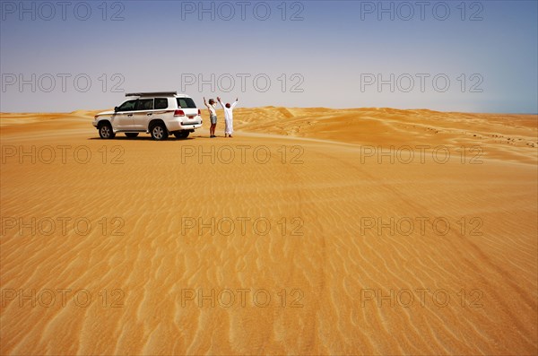 Tourist and Bedouin standing next to off-road vehicle