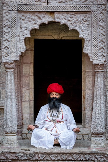 Man practicing yoga in a window at the stepwell Toorji Ka Jhalra Jodhpur