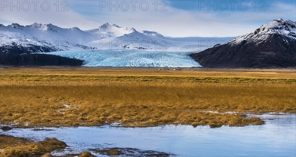 Icelandic farmstead with glacier tongue and snow-covered mountains