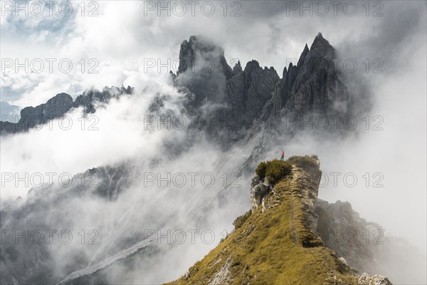 Woman in red jacket standing on a ridge