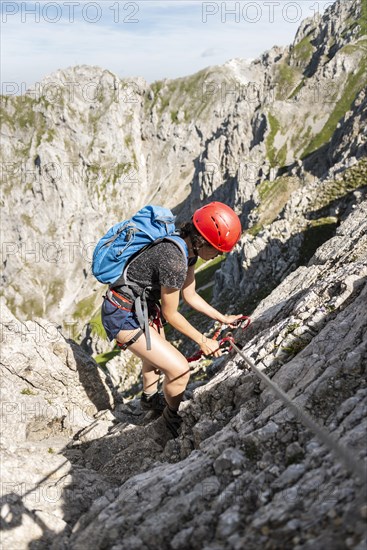 Mountaineer with helmet on a secured fixed rope route