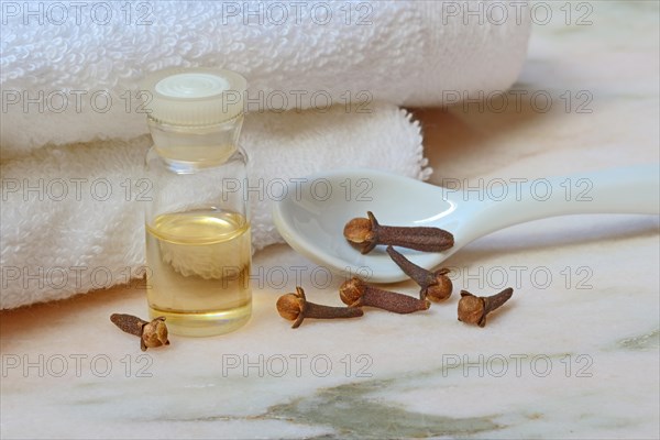 Clove oil in bottles and cloves on towel