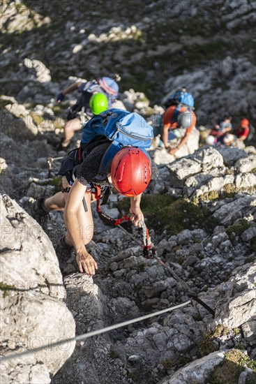 Group of mountaineers with helmet on a secured fixed rope route