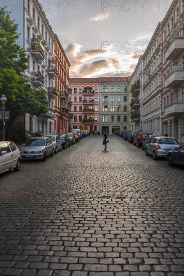 Man walking across cobblestone street in residential area