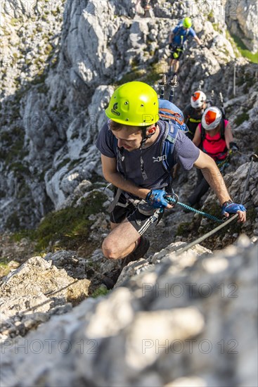 Mountaineer with helmet on a secured fixed rope route