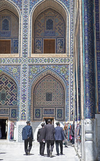 Men with Doeppi in the courtyard with pointed arch niches of the Ulug'Bek-Medrese