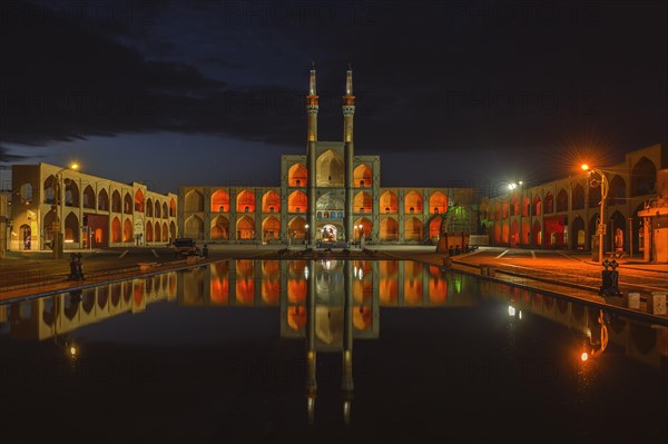 Amir Chaqmaq complex facade illuminated at sunrise and reflecting in a pond