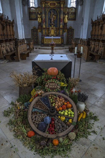 Wagon wheel decorated with vegetables for Thanksgiving in front of the high altar in the church