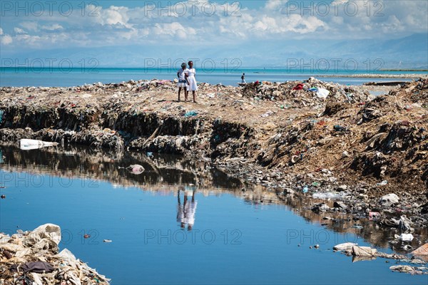 Girls on a huge mountain of rubbish on the coast