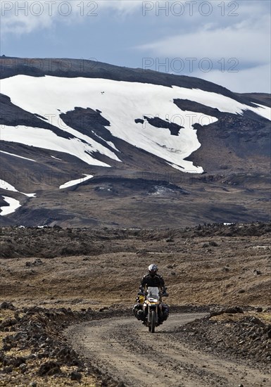 Motorbike on gravel road in desert-like landscape in the highlands in summer