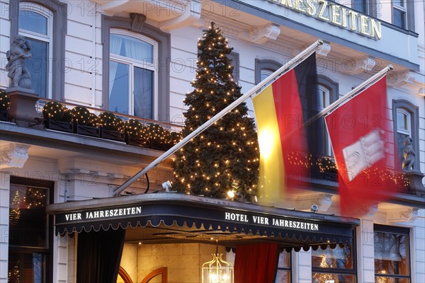 Entrance area with flag of Germany and Hamburg and illuminated christmas tree Hotel Vier Jahreszeiten