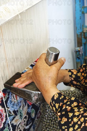 Iranian woman weaving a carpet