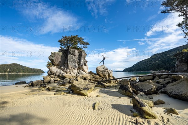 Young man standing with outstretched arms on a rock