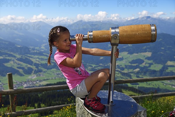 Girl looking through a wooden telescope