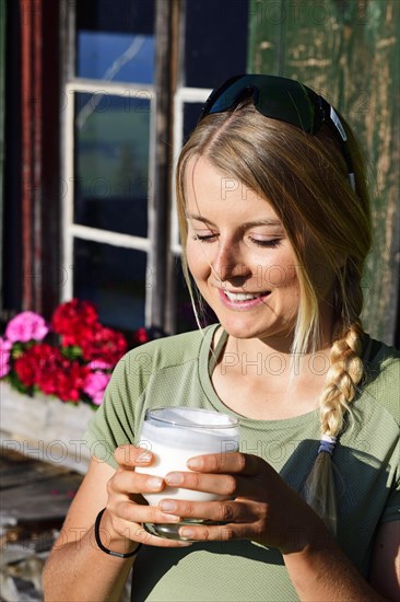 Young female hiker drinks buttermilk at the Kraftalm