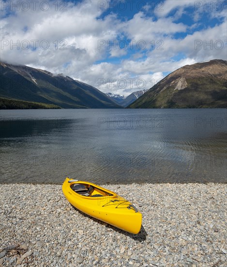 Yellow kayak on pebble beach