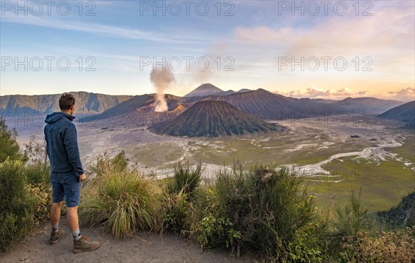 Young man in front of volcanic landscape at sunset