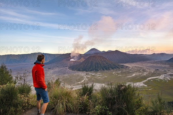 Young man in front of volcanic landscape at sunset