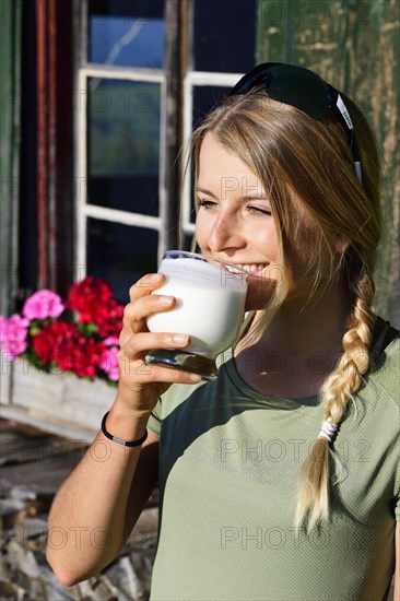 Young female hiker drinks buttermilk at the Kraftalm