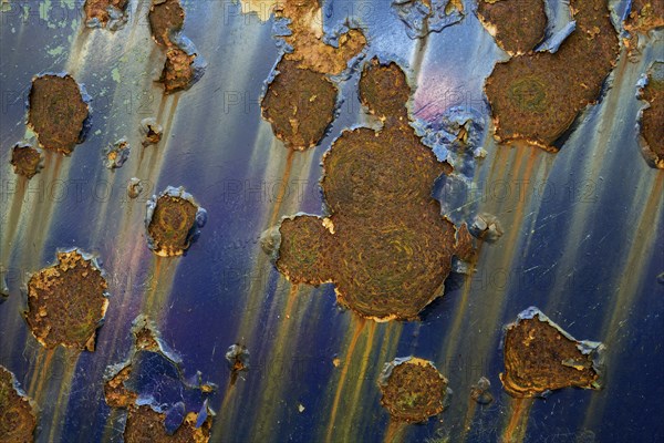 Flaked paint and rust spots on an old car door