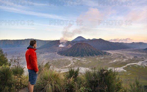 Young man in front of volcanic landscape at sunset