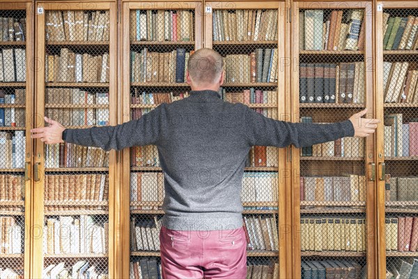 Man trying to grab the knowledge from the books on the bookshelves