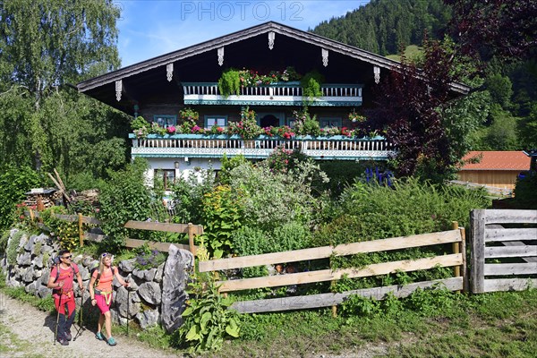 Hikers in front of a farmhouse above Sachrang