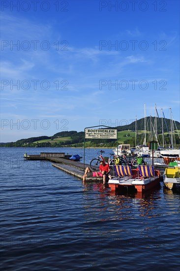 Couple with electric bikes pauses on a landing stage at Lake Obertrumer See