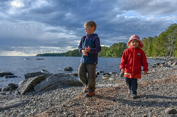 Little girl and boy playing in the open air by a lake