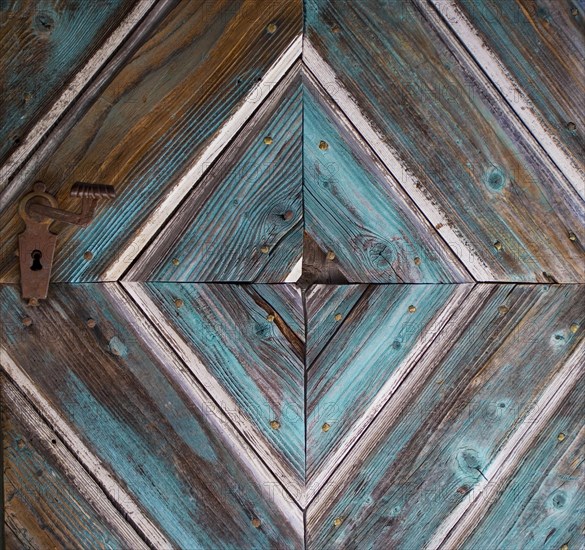 Old wooden house door with diamond-shaped pattern on a historical farmhouse